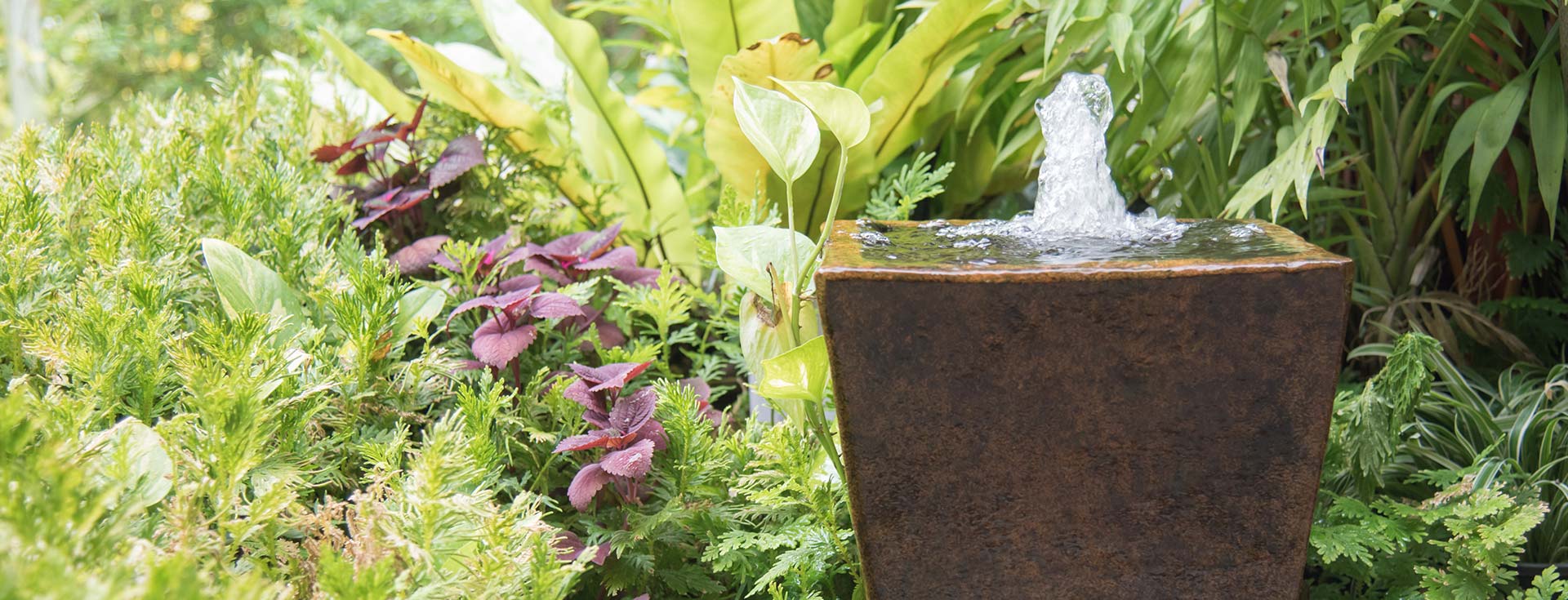 A fountain inside a cermic pot in a tropical garden